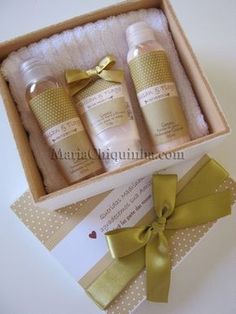 three bottles of body lotion sitting in a box next to a card and ribbon