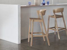 two wooden barstools in front of a counter with vases and flowers on it