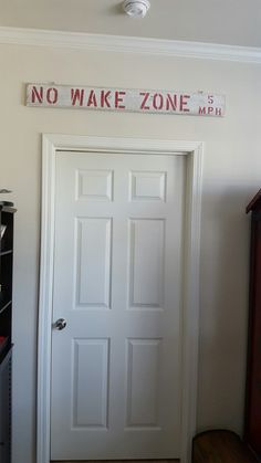 there is a white door with no wake zone on the wall above it and a red sign that says no wake zone