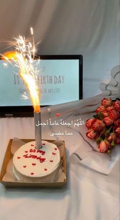 a birthday cake with a sparkler on it sitting in front of a laptop computer