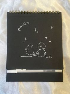 a notebook with a drawing of two people sitting under a stars and moon on it