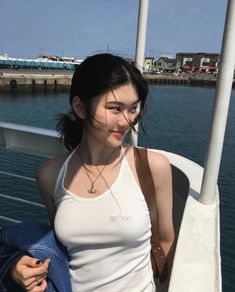 a woman in white tank top standing by the water