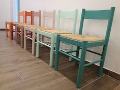 four wooden chairs lined up next to each other on the floor in front of a wall