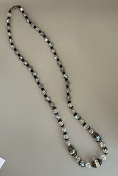 "Featuring this beautiful and sparkly, black and metallic silver, aurora borealis crystal necklace. The necklace measures 29\" in length and has a silver tone pearl clasp. There is nice detail to this necklace and it has some beautiful end caps. The necklace is in very good vintage condition. A beautiful piece!" Silver Long Beaded Necklace With Black Beads, Silver Crystal Necklace With Round Beads For Party, Faceted Silver Beaded Necklace For Party, Silver Beaded Necklace With Faceted Beads For Evening, Silver Faceted Crystal Beaded Necklaces, Silver Faceted Crystal Beaded Necklace, Faceted Crystal Silver Beaded Necklace, Silver Single Strand Crystal Necklace For Formal Occasions, Paper Beads Necklace