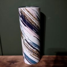 a white and blue striped vase sitting on top of a wooden table next to a green wall