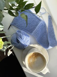 a blue crochet blanket next to a cup of coffee on a window sill