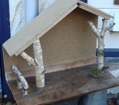 a house made out of birch trees on top of a wooden table in front of a building