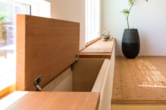 a vase sitting on top of a wooden counter next to a window sill with a plant in it