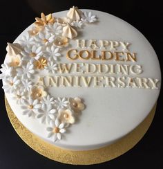 a white and gold wedding anniversary cake with flowers