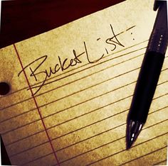 a note pad with the word bucket list written on it and a pen resting on top