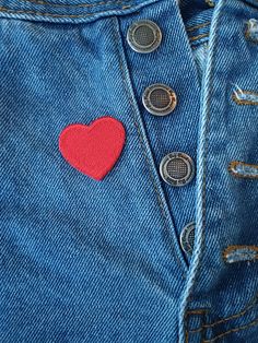 a red heart is on the back of a pair of blue jean pants with buttons