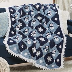 a crocheted blanket with snowmen on it sitting on a couch in front of a window