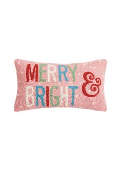 a pink pillow with merry and bright embroidered on the front, sitting against a white background