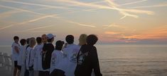 a group of people standing next to each other near the ocean