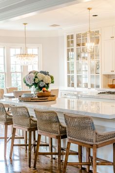 a large kitchen with white cabinets and marble counter tops, along with wicker bar stools