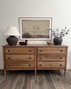 a wooden dresser with two vases and a lamp on it's sideboard