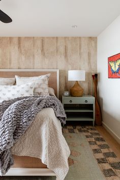 a bedroom with a bed, nightstand and ceiling fan