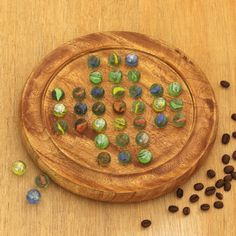 a wooden plate with glass beads on top of it next to coffee beans and seeds