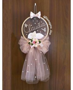 a wooden plaque hanging from the side of a door with a bow and name on it