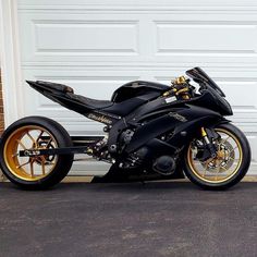 a black and gold motorcycle parked in front of a garage door with two yellow rims