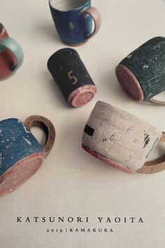 five different colored cups sitting on top of a white table next to eachother