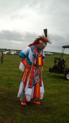 a man dressed in colorful clothing standing on top of a lush green grass covered field