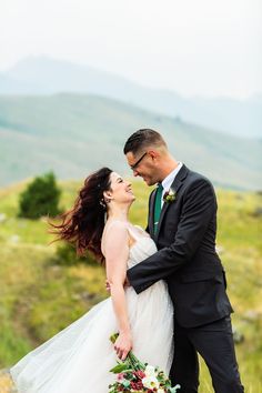 a bride and groom are standing in the grass