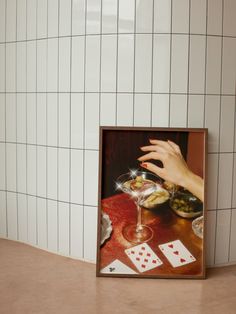 a woman's hand reaching for a glass of wine in front of playing cards