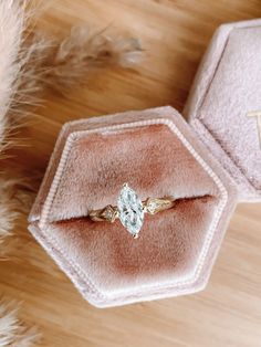 an engagement ring in a velvet box on top of a wooden floor with fur around it