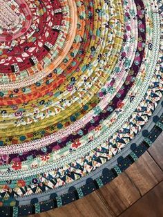 a multicolored round rug on the floor in front of a wooden flooring