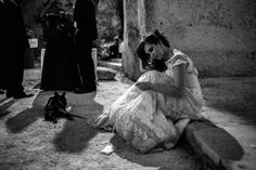 a black and white photo of a woman sitting on the ground with her head in her hands