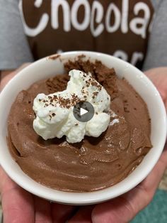 a person holding a white bowl filled with chocolate and whipped cream