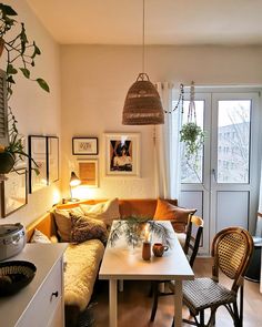 a living room filled with furniture and a white table topped with plants in front of a window