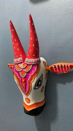 a colorful mask with horns hanging on the wall