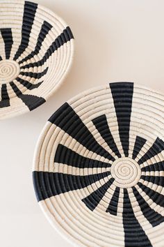 two black and white baskets sitting next to each other on top of a table,