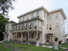 a large white house sitting on top of a lush green field next to tall buildings