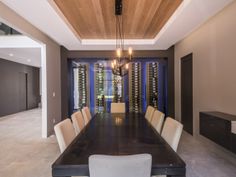 a dining room with a table and chairs in front of a wine rack on the wall