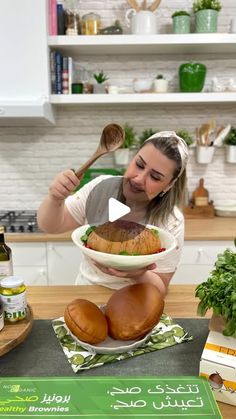 a woman holding a bowl filled with bread on top of a counter next to other food items