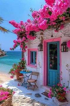 pink flowers are growing on the side of a house next to the ocean and beach