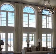 a living room with couches, tables and large windows overlooking the beach in front of them