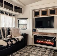 a living room with a couch, fireplace and television on the wall in front of it