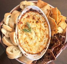 a bowl filled with cheese and crackers on top of a table next to bread