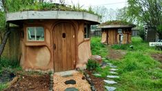 an outhouse with a green roof in the middle of some grass and rocks on the ground