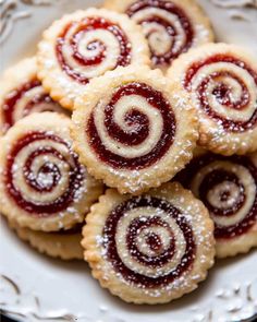 several small pastries on a white plate with powdered sugar and jelly toppings