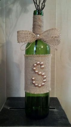 a wine bottle wrapped in burlap with a bow and pearls on the top