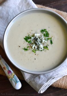 a white bowl filled with soup sitting on top of a table next to a napkin