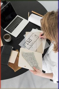 a woman sitting at a table working on some drawings