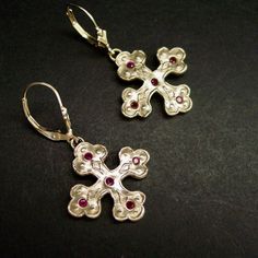 "Hand sculpted cross Byzantine earrings with embedded garnet reminiscent of ancient Greek jewelry The orthodox cross is a variation of the Christian cross since the 6th century in the Byzantine Empire. This is a square cross with clover tip shape ends. A cross with three circles or discs on each arm in a Christian context represents the Holy Trinity but was probably also copied from earlier Celtic Druidry, where the circles or rings represent the three dominions of earth, sky and sea. - Hand car Handmade Byzantine Crucifix Jewelry, Handmade Byzantine Style Crucifix Jewelry, Byzantine Sterling Silver Jewelry With Matching Earrings, Medieval Style Handmade Earrings For Gift, Silver Byzantine Pierced Earrings, Medieval Earrings, Byzantine Earrings, Byzantine Cross, The Byzantine Empire