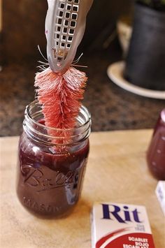 a jar filled with jam and a hair brush sticking out of it's top