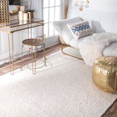 a living room with white walls and gold accents on the rug, two stools and a table